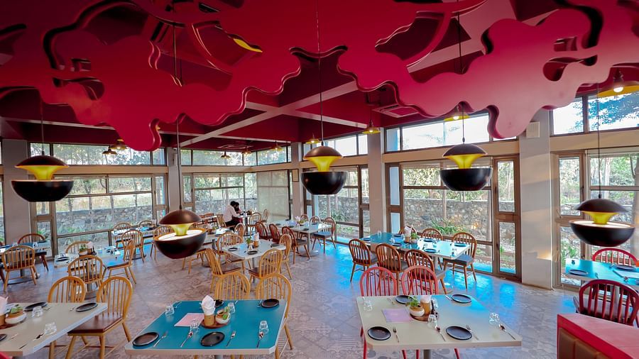 An image of a restaurant featuring chairs, tables, and hanging lights - Pride Resort Ambaji